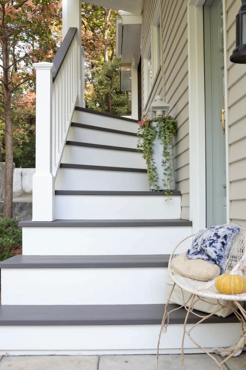 DIY couple painting outdoor stair railing together with drop cloths and brushes