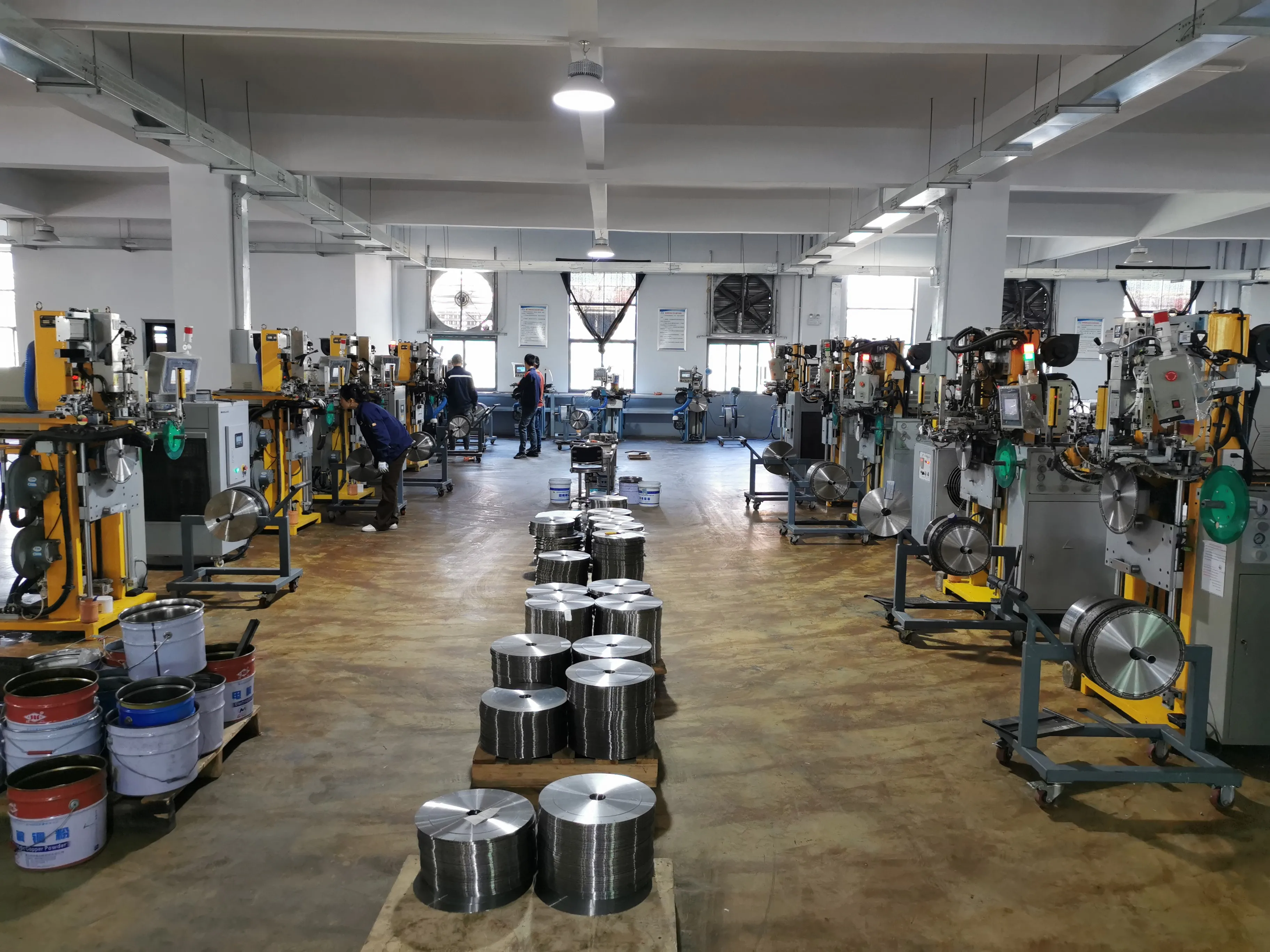 Saw blade production workshop with machinery and stacked blade cores