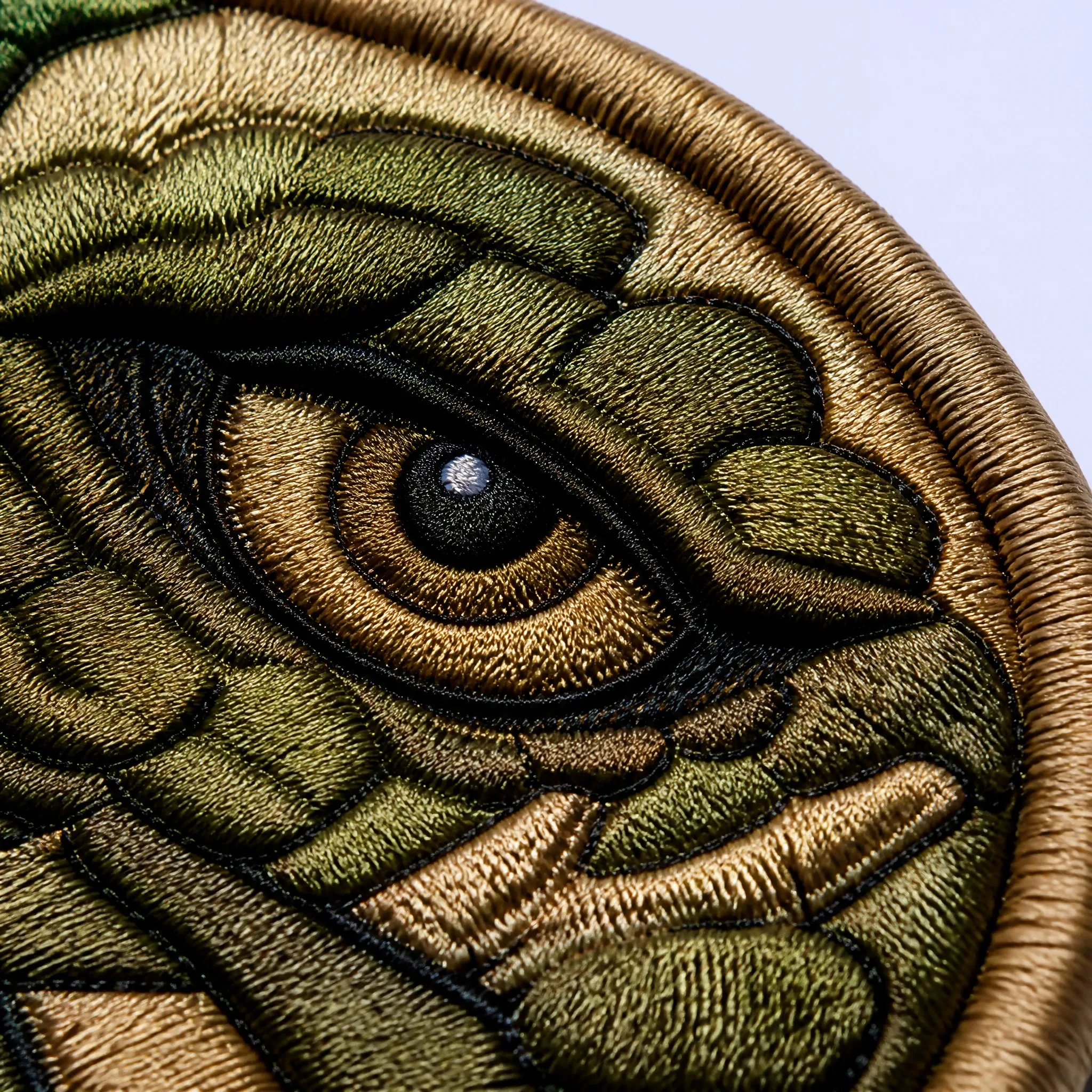 4K Macro Close-up of Intricate Metallic Gold and Tactical Olive Drab Green Embroidery Stitching on Wolf Eye