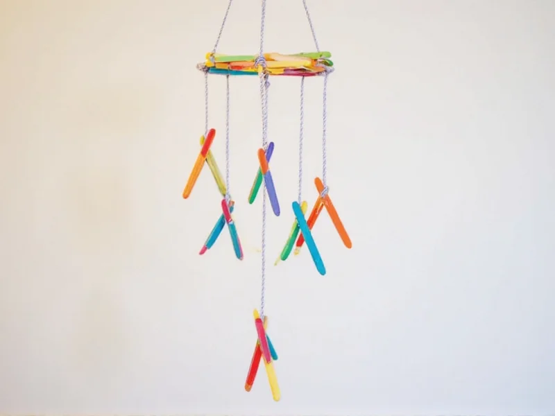 Colorful geometric mobile hanging from popsicle sticks with dental floss