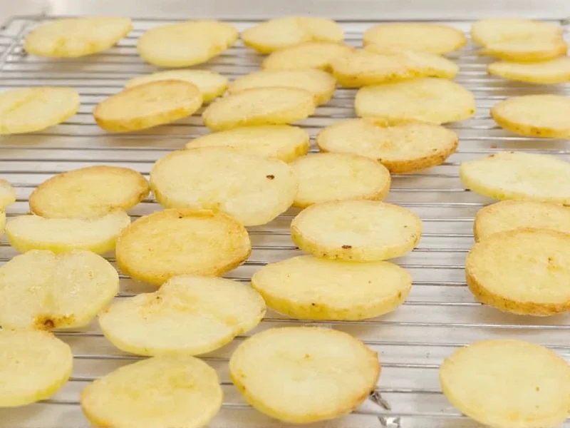 Potato slices drying on wire rack before frying
