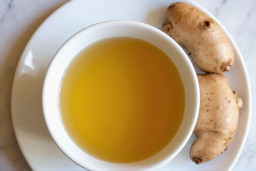 Steaming cup of ginger tea with lemon slice and fresh ginger root on wooden table