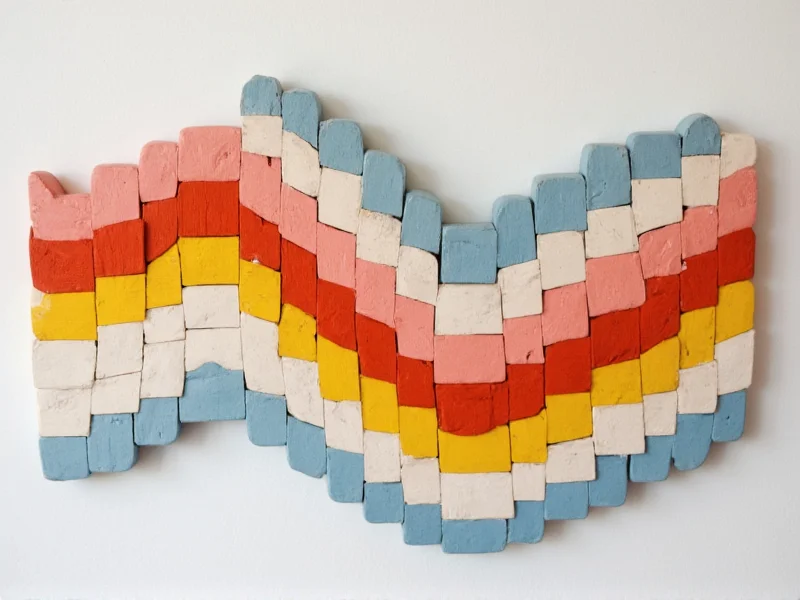 Geometric wall art made from painted wooden blocks arranged in wave pattern