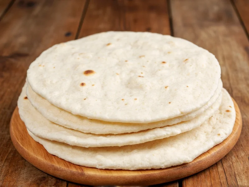 Freshly made handmade flour tortillas stacked on wooden board