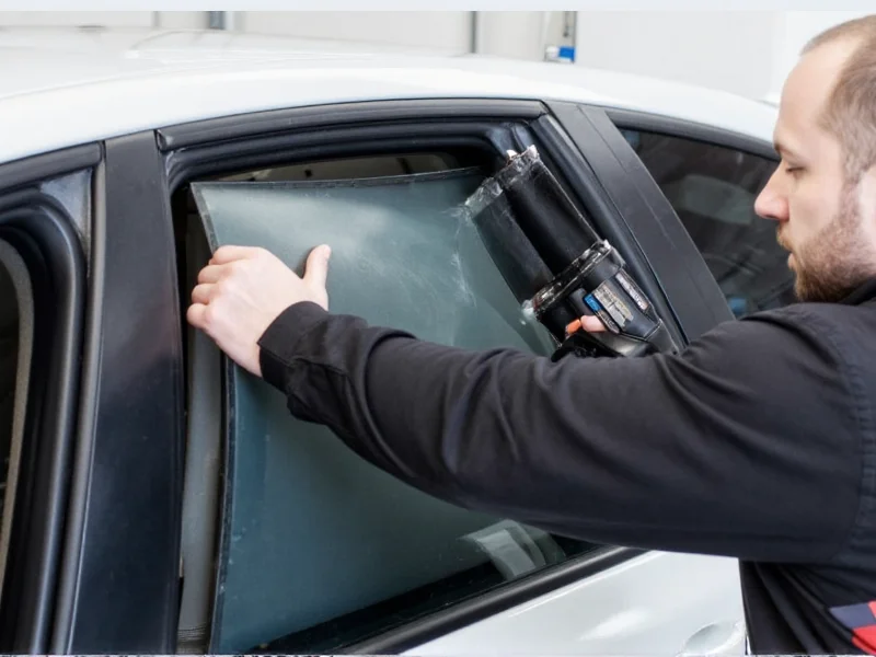 Applying car tint film with heat gun on sedan window