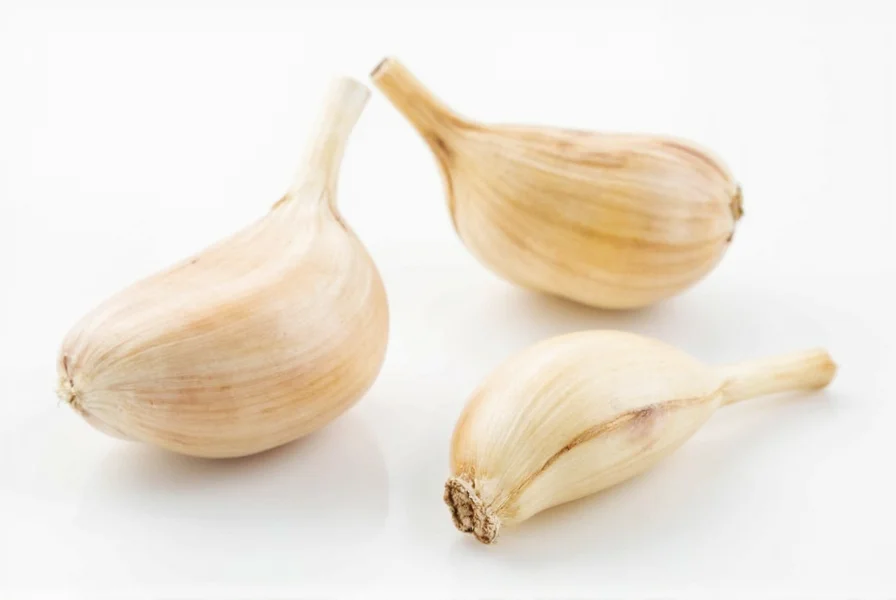 Chef's hand mincing three garlic cloves on wooden cutting board