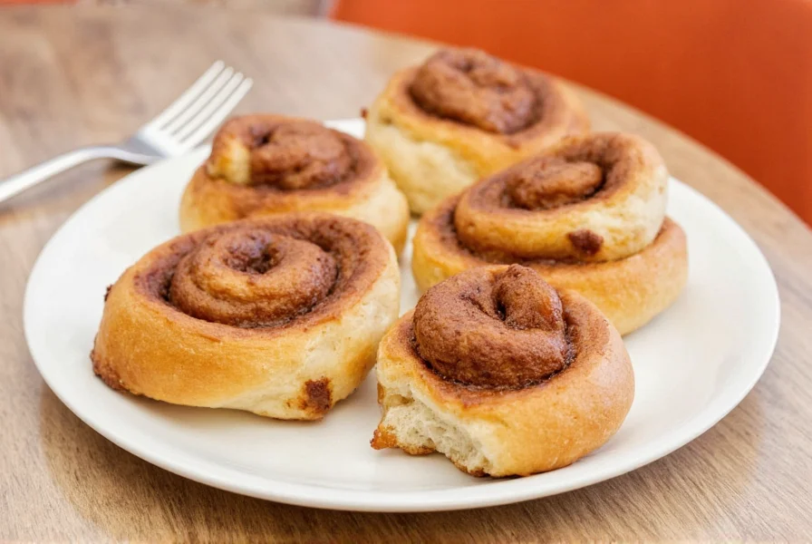 Assortment of freshly baked cinnamon buns with different toppings including pecans, walnuts, and caramel drizzle on white ceramic plate