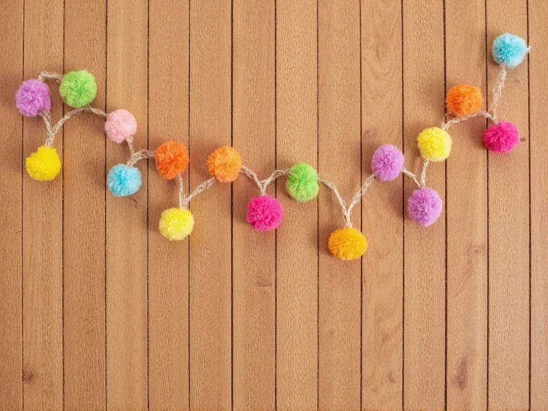 Colorful pom-pom garland hanging on wooden wall