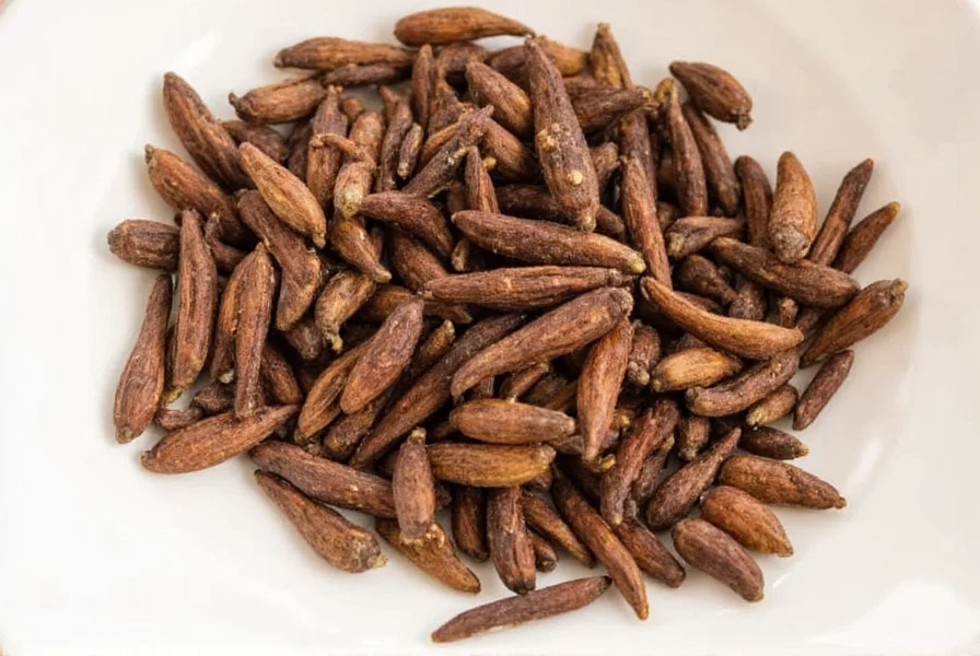 Whole cloves and ground cloves displayed next to traditional Indian spices