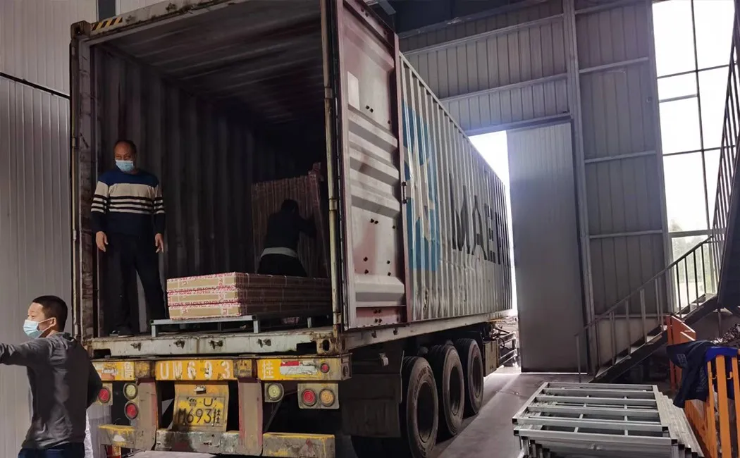flat-pack steel locker cartons being loaded into a shipping container at factory — export ready