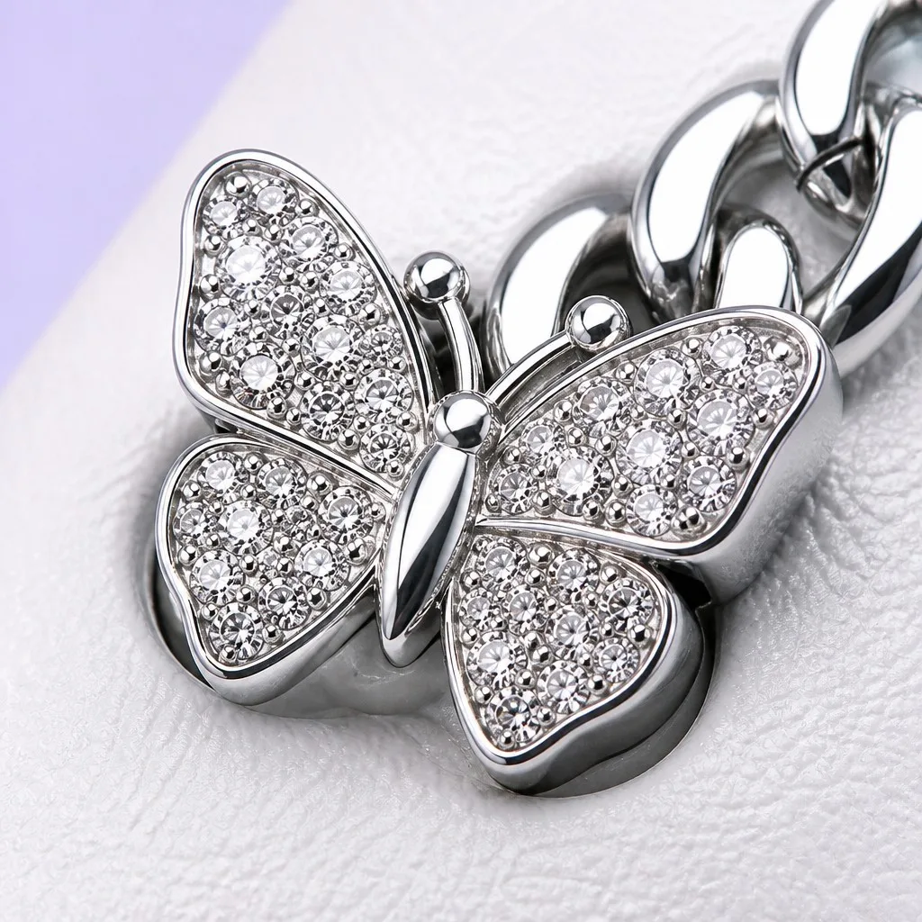 Macro view of a pavé crystal butterfly charm with a polished metal curb chain