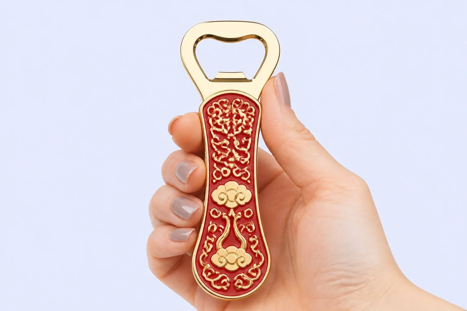 Red enamel bottle opener with gold filigree held in hand