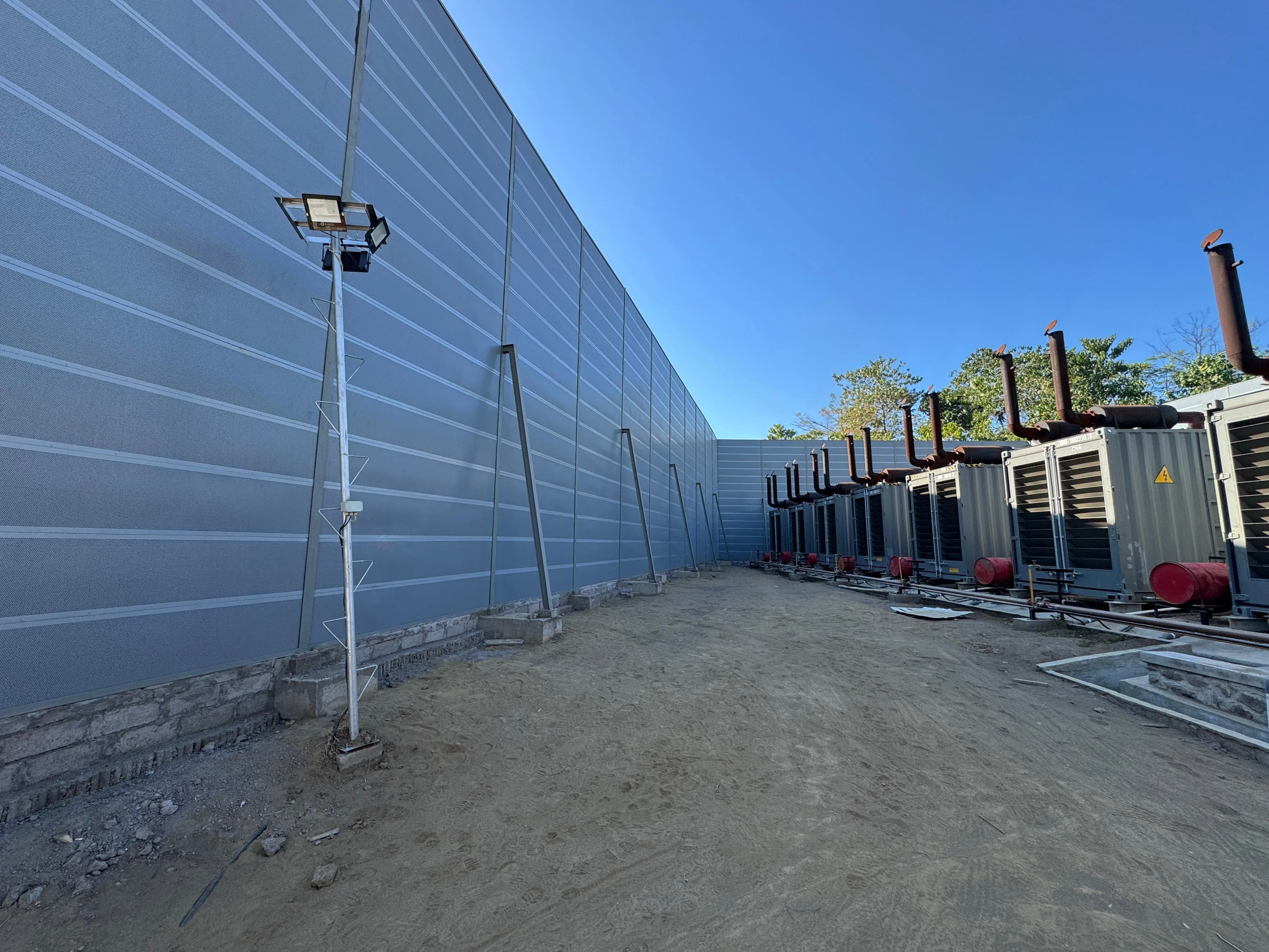 Long 8 m high micro-perforated acoustic panel barrier facing power generation units