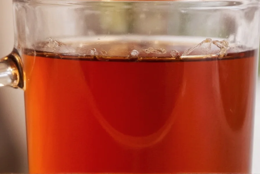 Close-up of Starbucks Shiku Raspberry Herbal Tea in a clear glass mug showing the deep amber color of the brewed tea