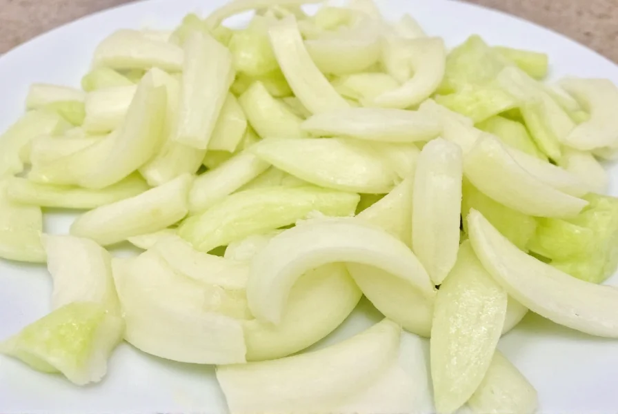 Close-up of perfectly sliced fennel showing different cutting techniques: thin slices, wedges, and julienne cuts arranged on white plate