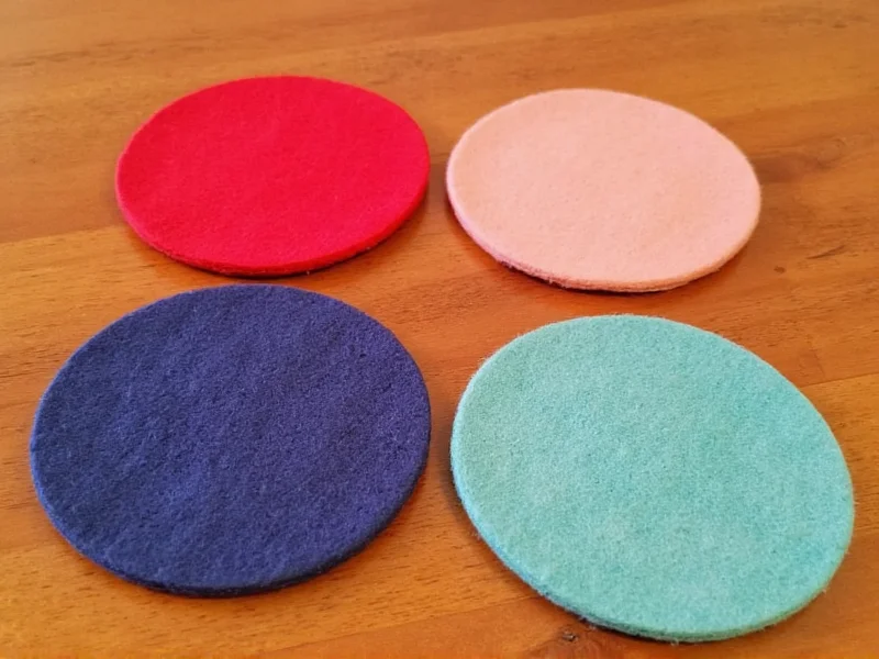Set of four colorful felt coasters on wooden table