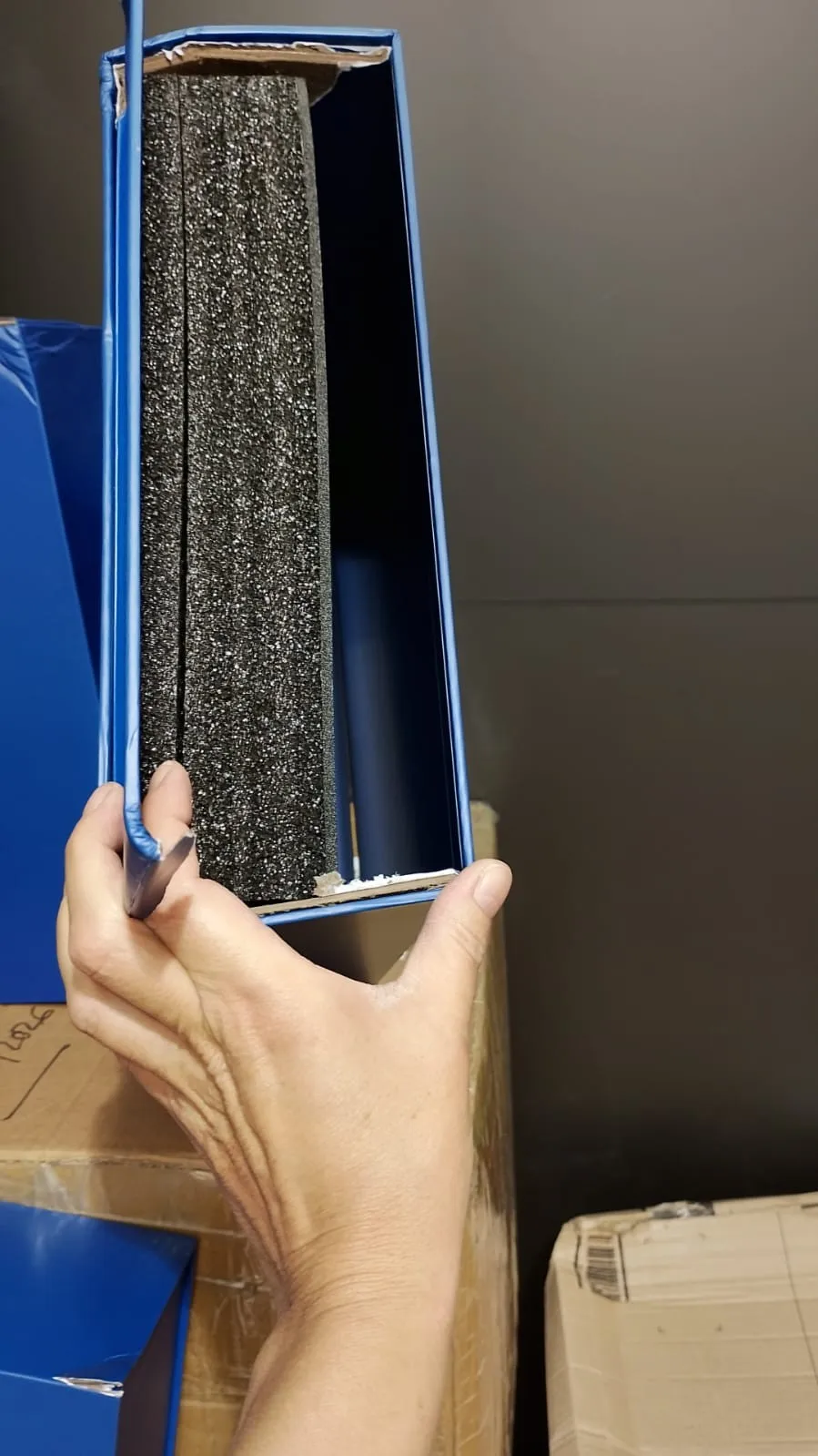Corner bursting defect on rigid box — cracked edge exposing greyboard, structural packaging failure