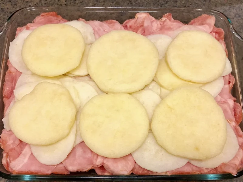 Layering potatoes and ham in baking dish