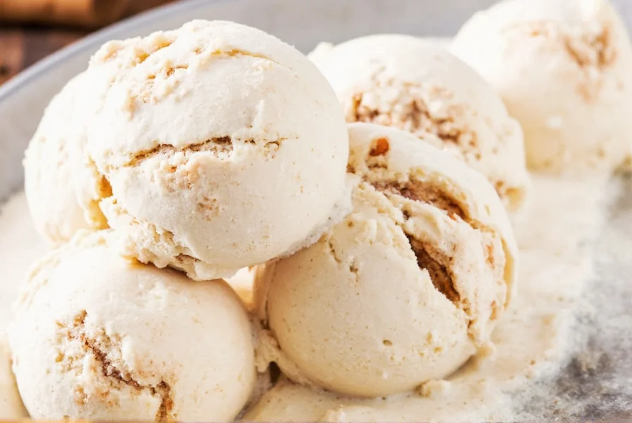 Close-up of cinnamon roll ice cream showing vanilla base, cinnamon swirls, cream cheese ribbon, and dough pieces in a waffle cone