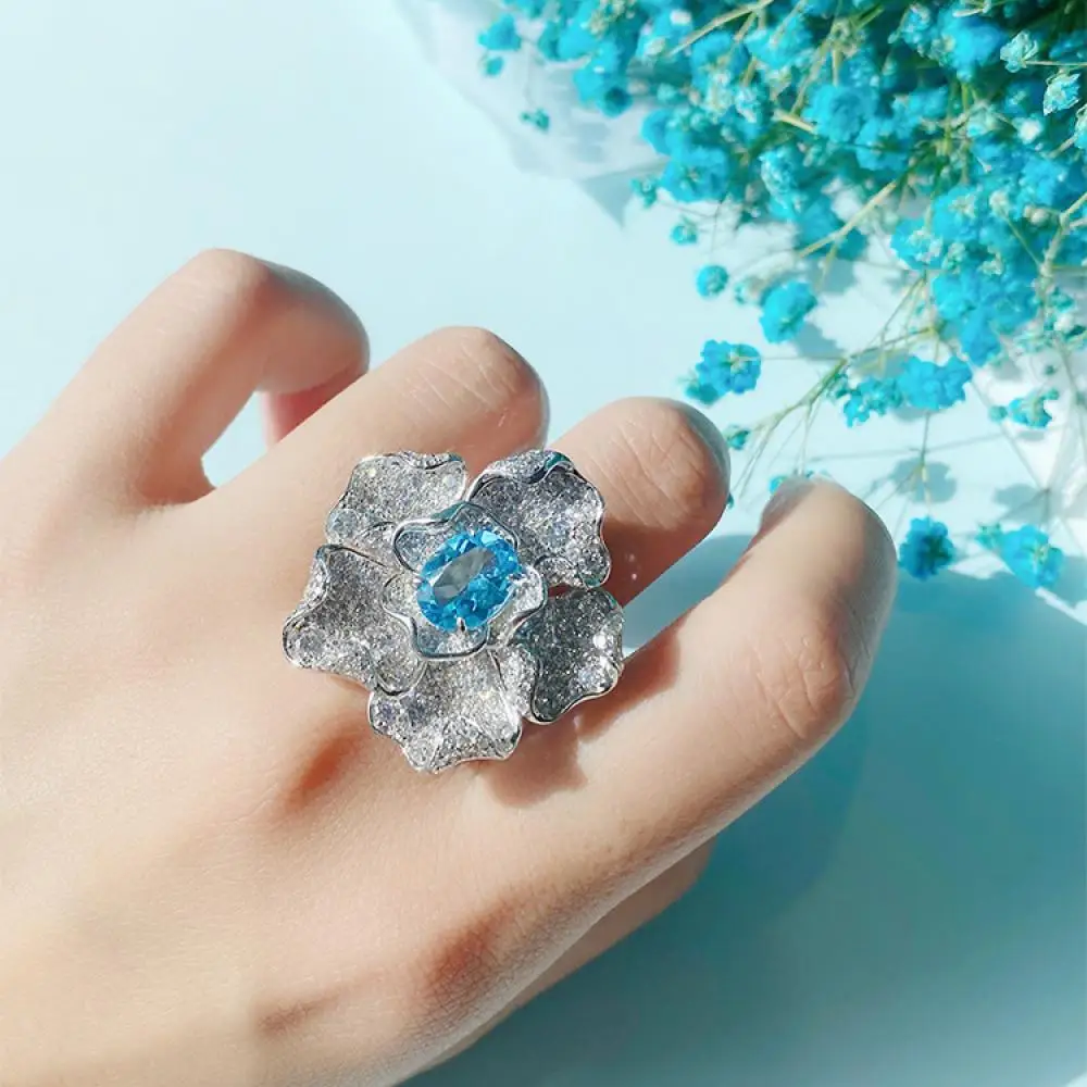 

Premium Customized Luxury Diamond Sea Blue Swiss Blue Topaz Flower Pigeon Egg Ring S925 Silver Color Jewelry for Woman