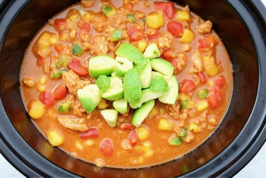Colorful bowl of white chicken chili with avocado garnish in slow cooker