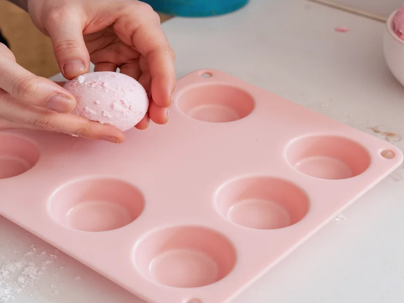 Hands pressing bath bomb mixture into silicone mold