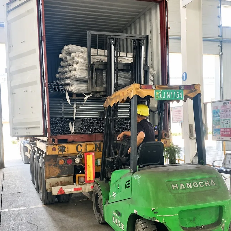 Forklift loading greenhouse structure packages into a shipping container.