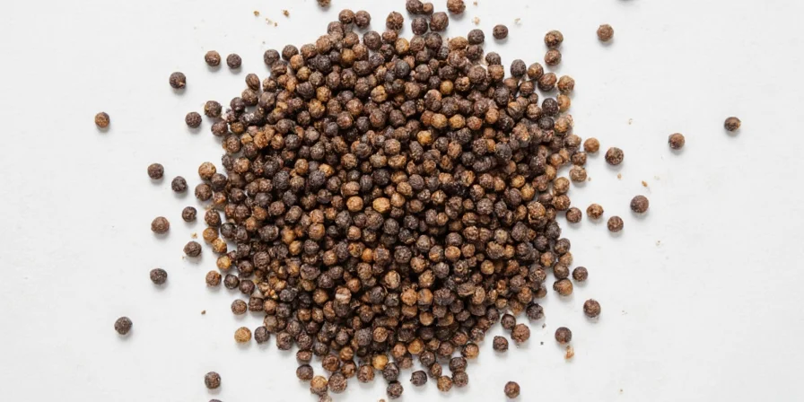 A modern kitchen spice rack showing cracked black pepper in a glass jar
