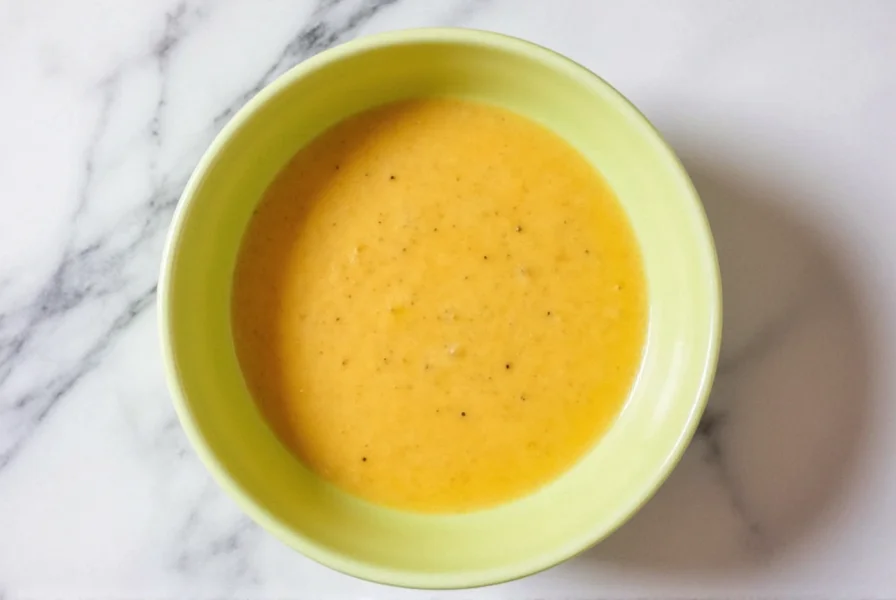 Glass jar containing vibrant ginger salad dressing stored in refrigerator with fresh ingredients nearby