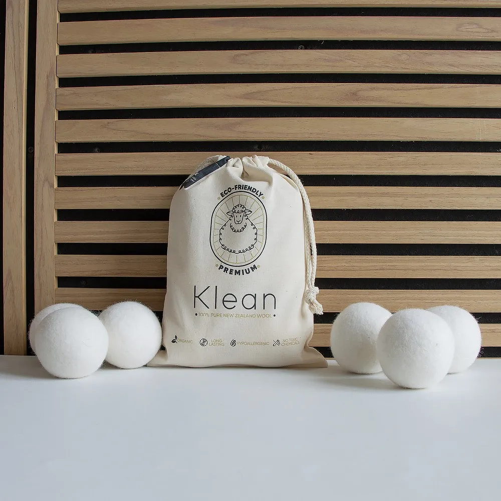 Custom printed cotton pouch with logo beside six white wool laundry balls on a white surface