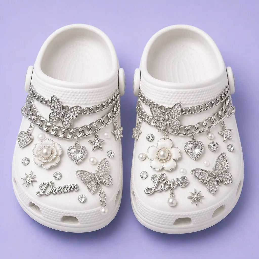 Matched pair of white clogs dressed with silver curb chains, crystal butterflies, pearl flowers and script charms