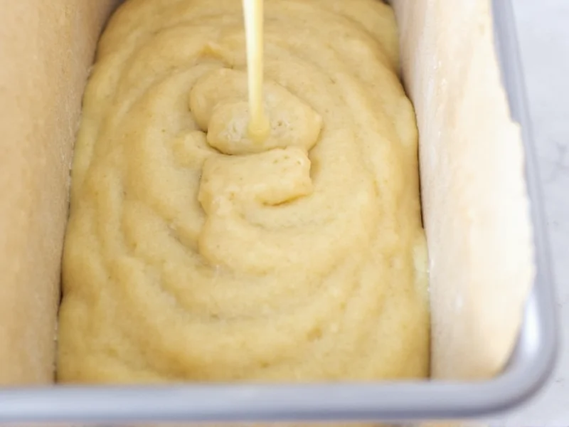 Pound cake batter being poured into loaf pan