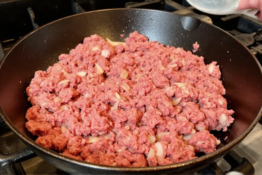Perfectly browned ground beef in cast iron skillet with onions and garlic for best beef chili recipe