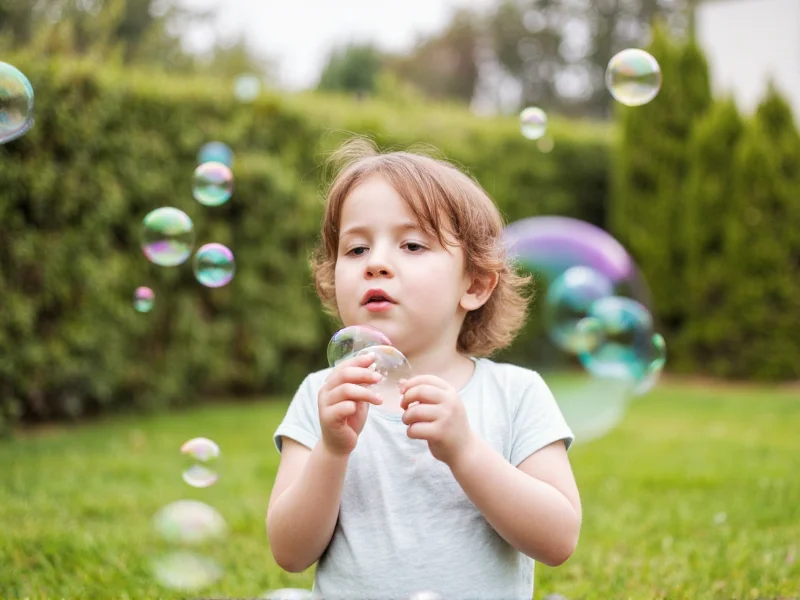 Child blowing giant bubbles in backyard on sunny day