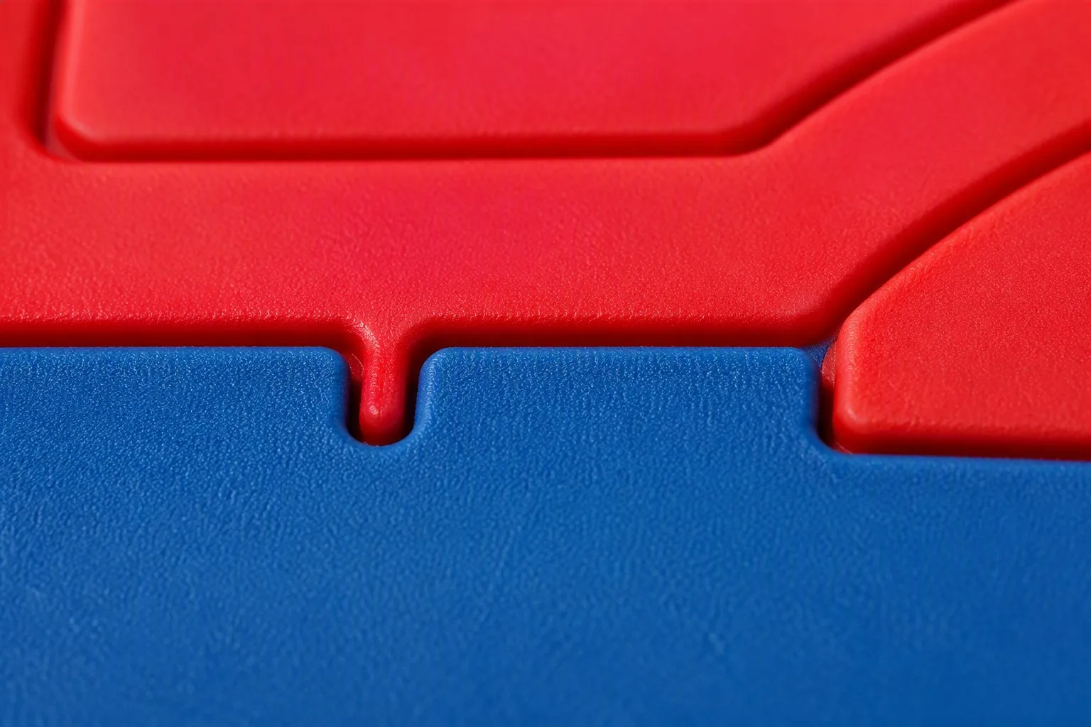 Close-up of PVC rubber keychain showing wave-cut seam between red and blue layers