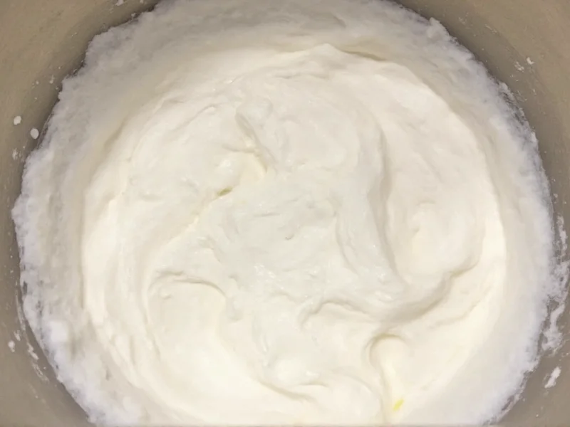 Whipped cream showing soft peak texture in mixing bowl