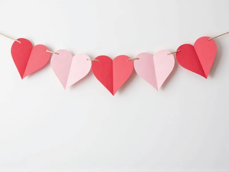 Recycled paper heart garland hanging on white wall