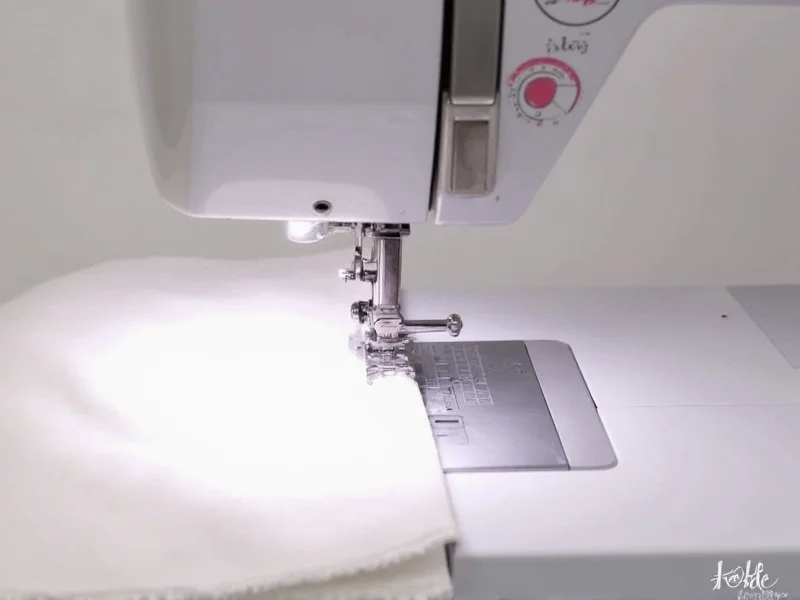 Sewing machine creating curtain hem with visible stitch pattern