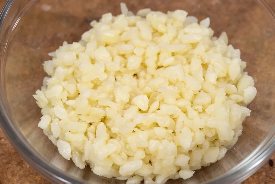 Fresh minced garlic in measuring spoon showing precise 1.5 teaspoon measurement