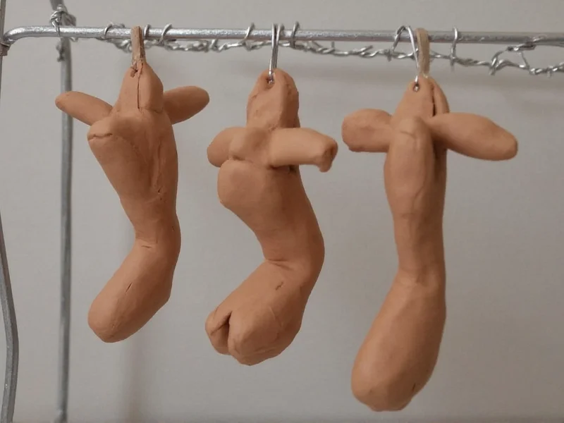 Three homemade clay sculptures drying on wire rack