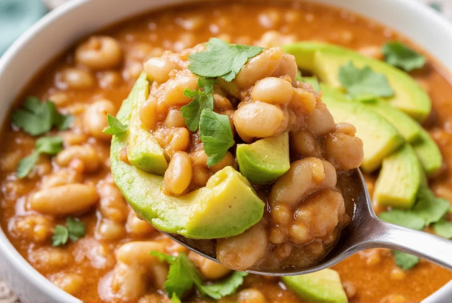 Serving of white bean chicken chili in bowl with avocado slices and cilantro garnish, showing creamy texture and vibrant colors