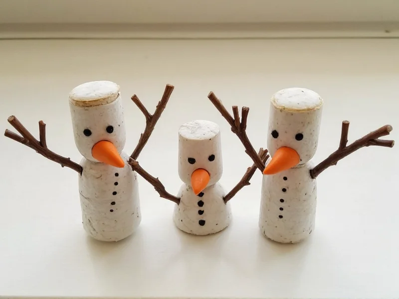 Three miniature snowmen crafted from wine corks with twig arms