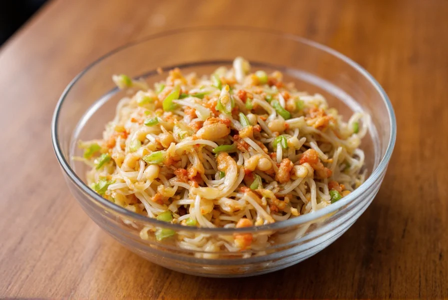 Fresh mung bean sprouts tossed with red chili paste in a glass bowl on wooden table