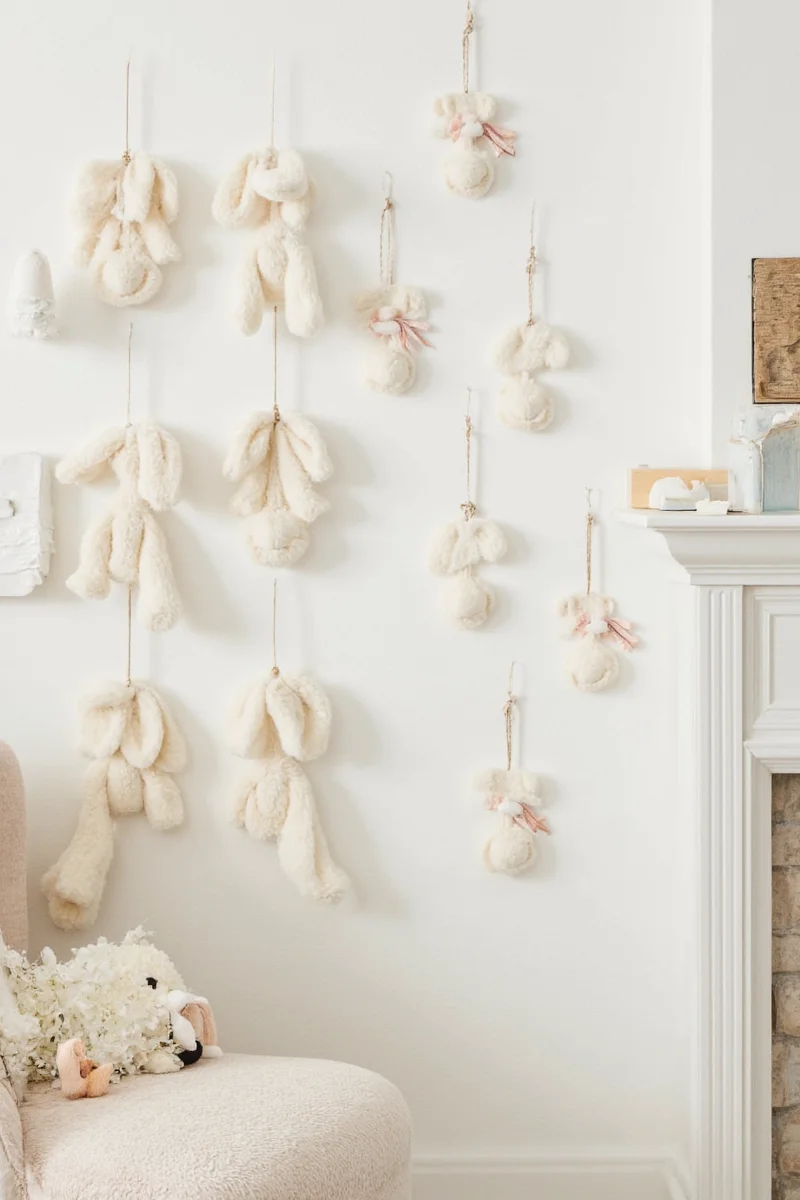 A smiling woman holding a plush bunny, surrounded by a variety of bunny-themed decor items in her living room.