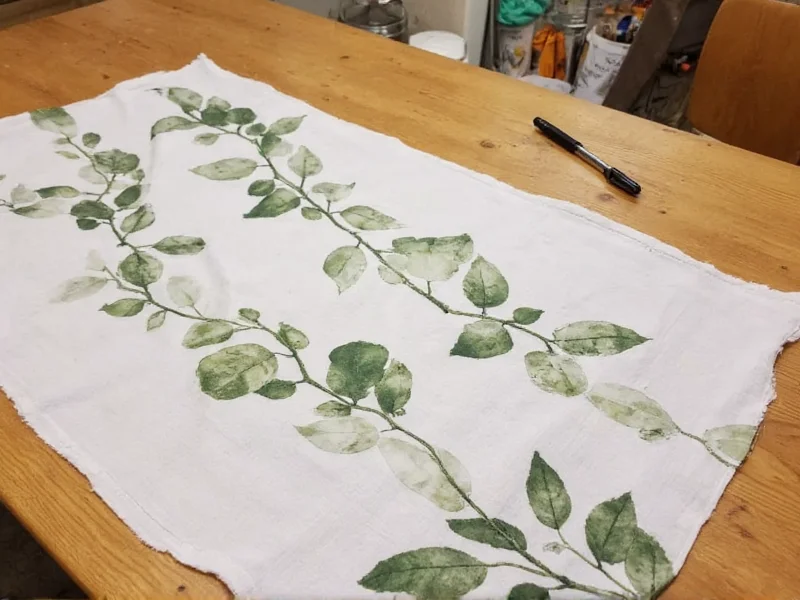 Handmade eco-printed fabric with leaf patterns on wooden table