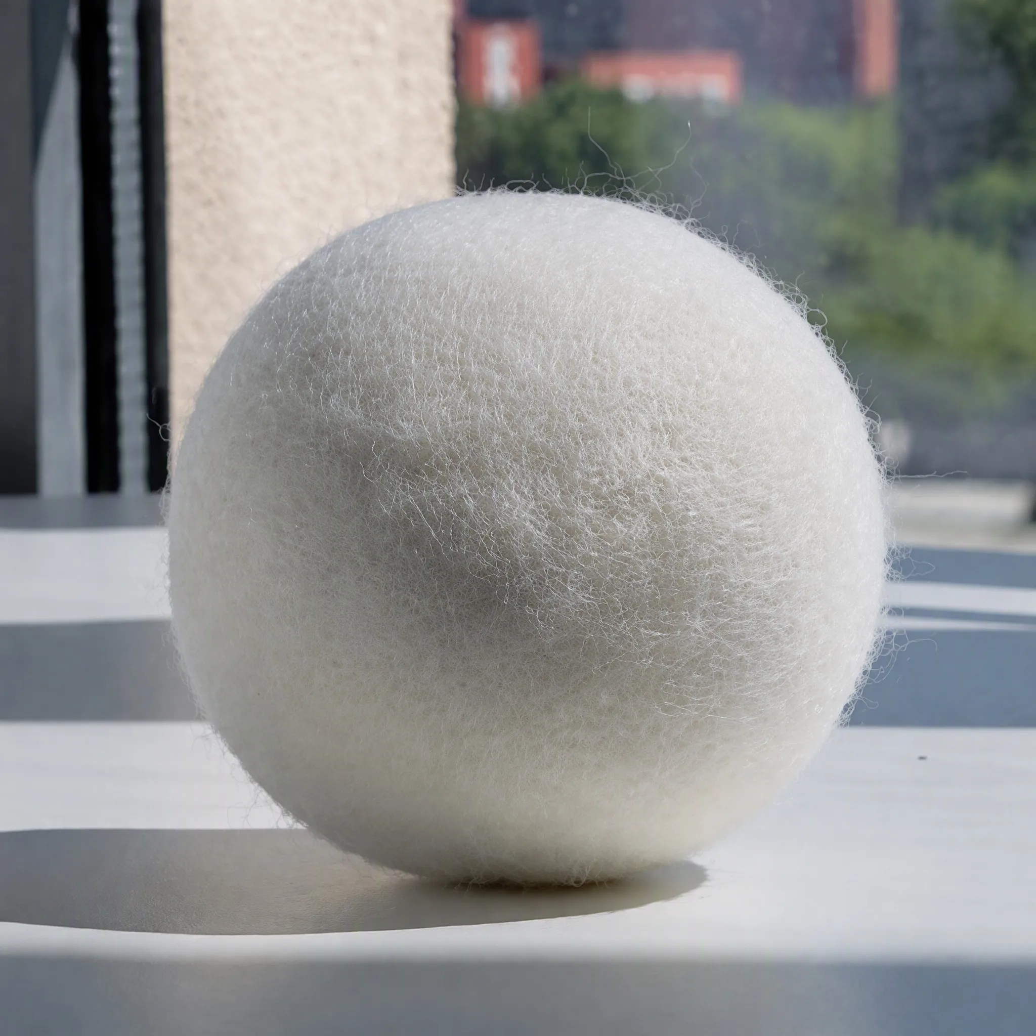 Macro close-up of a felted wool dryer ball showing dense 100% New Zealand wool fibre