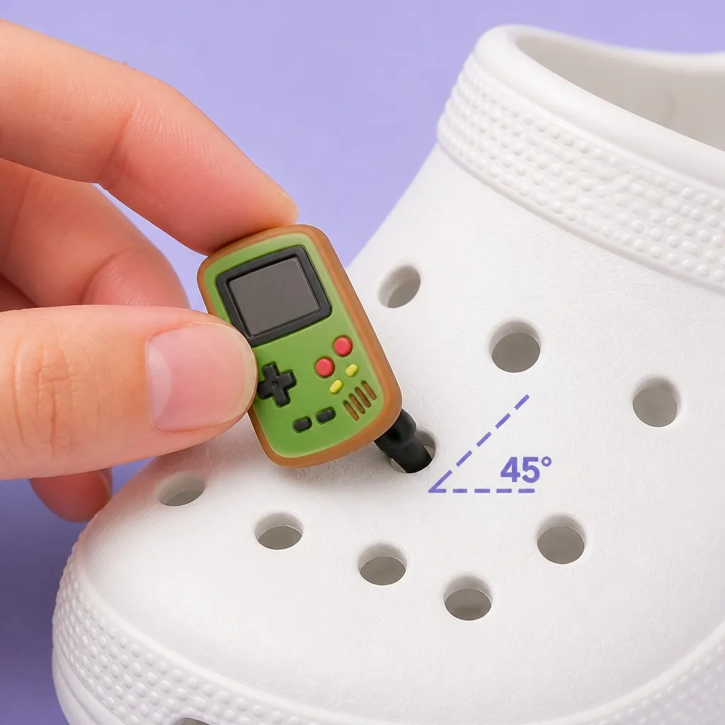 Hand inserting a retro handheld console charm into a clog hole at a 45 degree angle