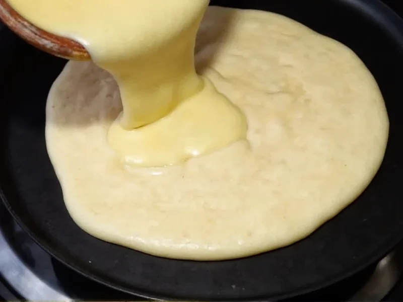 Homemade pancake batter being poured on griddle
