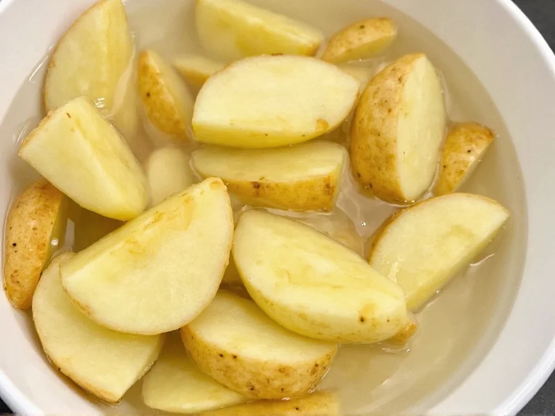 Potato wedges soaking in bowl of ice water