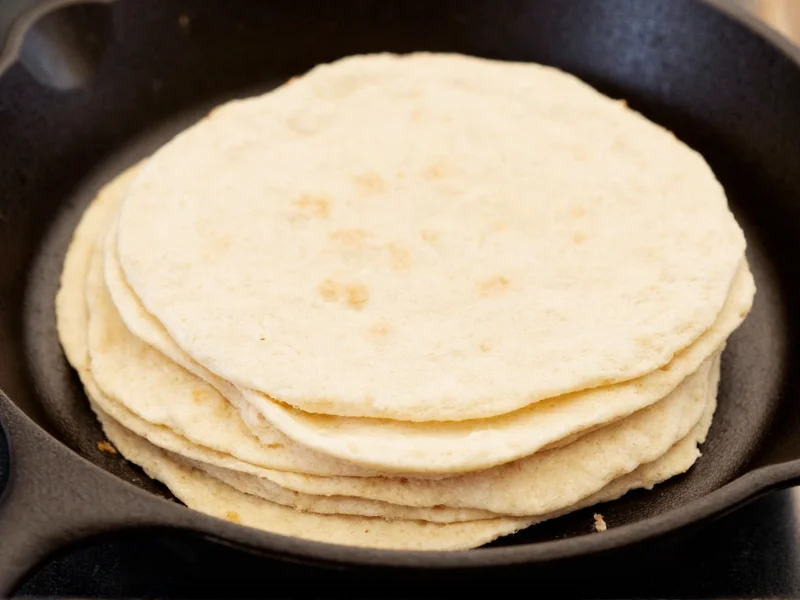 Homemade flour tortillas stacked on cast-iron skillet